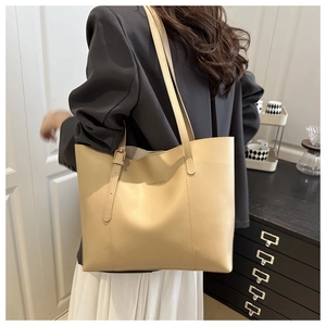 Detail of minimalist beige tote bag with shoulder straps and decorative side metal buckles