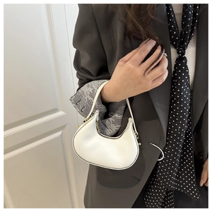 Detail of white half-moon hobo bag with gold hardware and slim handle held by model