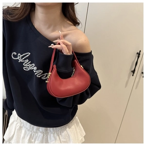Close-up of red leather crescent mini bag with golden zipper held by a model