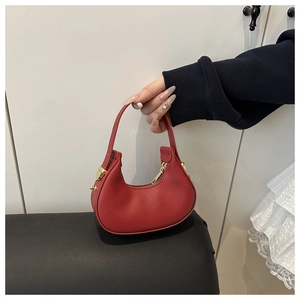 Detail of red crescent leather handbag featuring elegant gold hardware and top handle