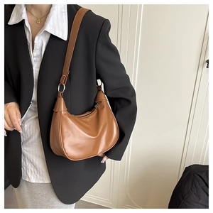 Detailed view of the smooth brown leather texture and silver metal rings on a crescent bag