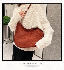 Detail of reddish brown matte shoulder bag with silver buckle worn with a knit sweater
