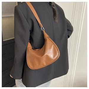 Detail view of the brown crescent bag's metal ring and shoulder strap attachment
