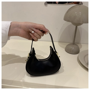 Detail of a black leather mini hobo bag with gold hardware and a zipper closure