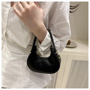 Close-up of a minimalist black hobo bag with gold hardware and a smooth leather finish