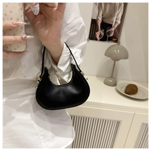 Detail of a black glossy leather hobo bag with gold zipper and smooth rounded silhouette
