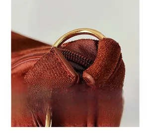Close-up of golden hardware ring and zipper on matte suede texture shoulder bag