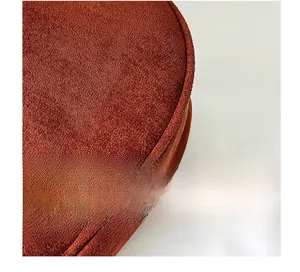 Macro detail of rust red textured fabric with precise stitching on a round shoulder bag