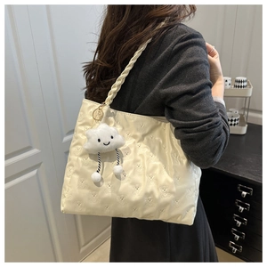 Detail of cream tote bag featuring bear embossed pattern and cloud plush charm