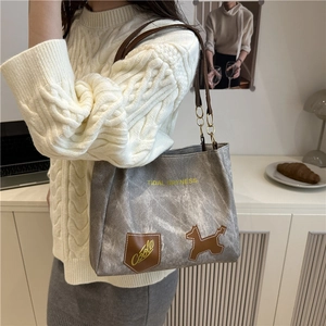 Borsa tote in tela grigia con manici in pelle marrone e patch cane in un accogliente caffè