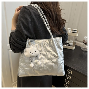 Detail of silver metallic tote bag featuring quilted bear patterns and woven straps