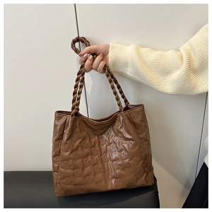Detail view of brown tote bag with embossed bear pattern and woven rope handles