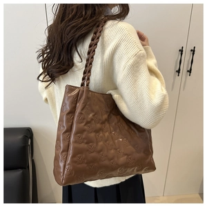 Detailed macro view showing the unique bear pattern texture on the brown leather tote bag