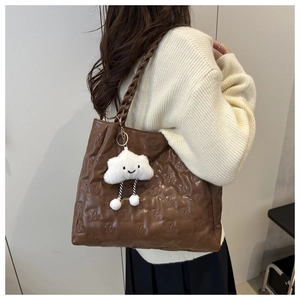 Close-up of brown tote bag with teddy bear embossing and woven strap detail