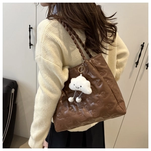 Detail of dark brown tote bag with bear embossed pattern and woven shoulder strap