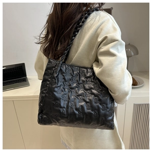 Detail view of large black tote bag featuring embossed teddy bear patterns and braided handles