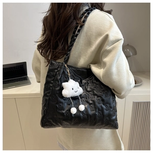 Detail of black embossed bear tote bag with a cloud plush charm for casual commuting