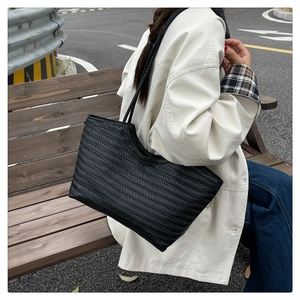 Detailed view of black woven tote bag texture with V-shaped pattern in a lifestyle setting