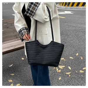 Dettaglio della trama intrecciata nera e del design spazioso della borsa tote in pelle