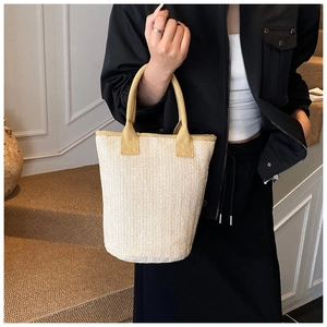 Detail of beige woven bucket bag with V-shaped knitting and yellow top handles