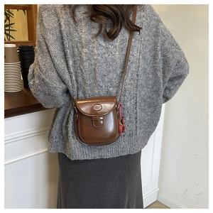 Detail of vintage brown semi-circle leather bag with a cute strawberry charm accessory