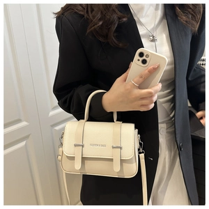 Détail du sac bandoulière blanc crème en cuir avec boucle en métal et lettrage mode