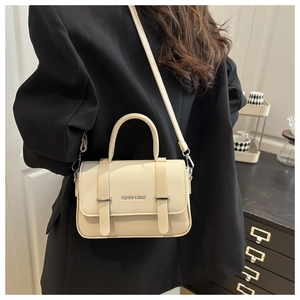 Détail du sac bandoulière blanc crème en cuir avec texture litchi et bijoux argentés