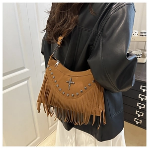 Detail view of brown suede crossbody bag with vintage rivets, long fringe and cross buckle