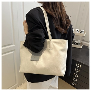 Detail of soft cream white tote bag with natural leather texture and gray hanging tag