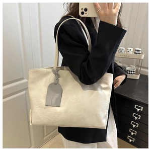 Detail view of large off-white tote bag featuring natural wrinkled texture and decorative tag
