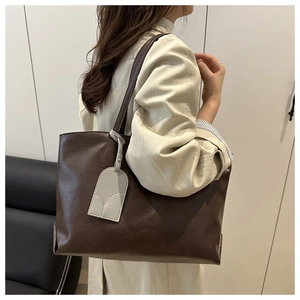 Close-up of brown soft leather tote bag with a gray hanging tag and pebbled texture