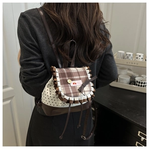 Detail of cute mini backpack showing brown plaid flap, lace trim and cherry embroidery