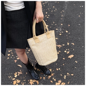 Close-up of beige woven bucket bag with sturdy round handles for a casual resort style