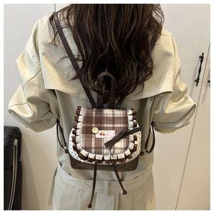 Close-up of checkered mini backpack with lace ruffles and brown bow on model back