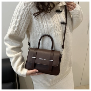 Détail du sac boîte marron foncé avec cuir grainé et inscription mode sur lanière