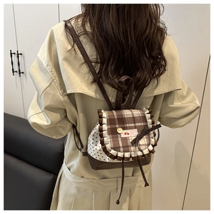Detail of British plaid backpack showing lace trim, cherry label, and drawstring closure