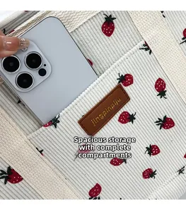 Detail of white corduroy tote bag with strawberry print and outer pocket for smartphone