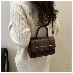Détail du sac marron foncé à motif litchi avec texte Fashion & Bags porté par le mannequin