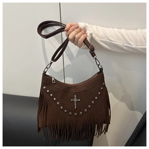 Close-up of brown suede bag featuring hanging fringes, metal studs and cross pendant