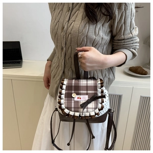 Detail of cute brown plaid backpack with cherry embroidery and white ruffle trim