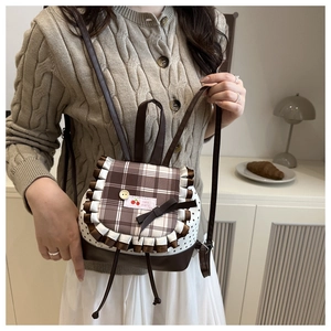 Detail of sweet-style mini backpack with plaid lid, white ruffles, and cherry patch