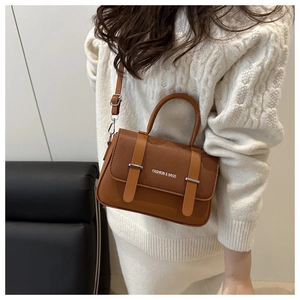 Sac bandoulière en cuir grainé marron avec texte blanc porté par le mannequin