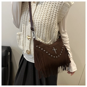 Detail of dark brown suede shoulder bag featuring bohemian tassels and rivet accents