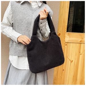 Detalle del bolso tote de pana negra suave mostrando su textura de canalé y asa ancha