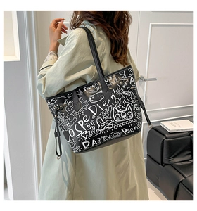 Elegante borsa tote in pelle nera con motivi graffiti bianchi abbinata a un cappotto beige