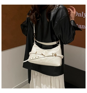 Detail of cream glossy leather shoulder bag with gold metal ring buckle and decorative strap