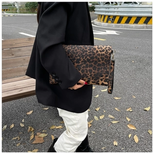 Detail shot of a leopard print envelope clutch bag with metal hardware and wrist strap