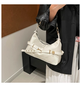 Detail of white glossy leather hobo bag with gold buckle on a model in a black blazer
