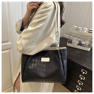 Detail of black quilted tote bag with chain strap and Canres & Hexa logo label