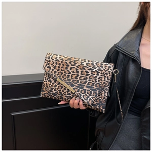 Dettaglio della borsa a busta leopardata con finiture dorate e cinturino da polso